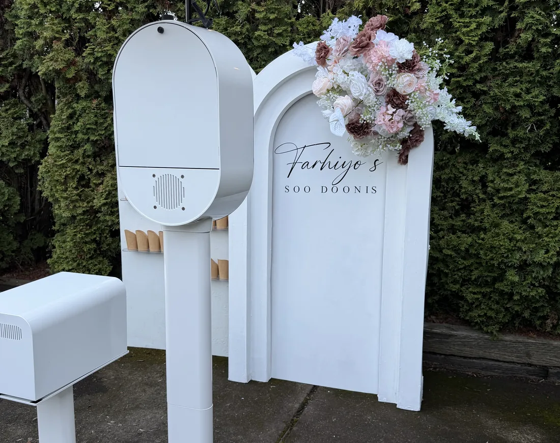 The photo booth set up outdoors beside a floral arrangement.