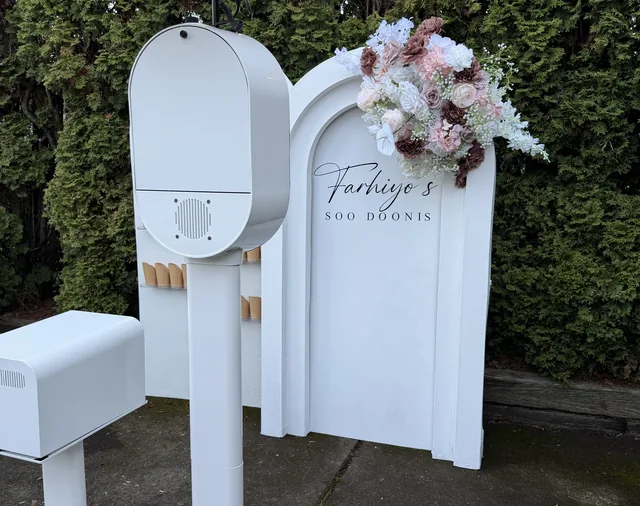 The photo booth set up outdoors beside a floral arrangement.